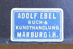 - (Adolf Ebel Buch- & Kunsthandlung), Etikett: Name, Berufsangabe/Titel/Branche, Ortsangabe; 'Adolf Ebel / Buch- & / Kunsthandlung / Marburg i. H.'. 